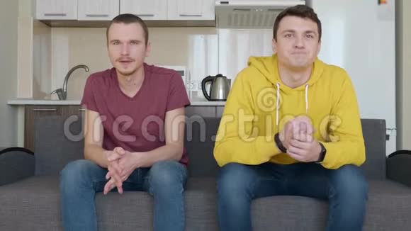 两个人坐在沙发上看着足球比赛的决定性时刻视频的预览图