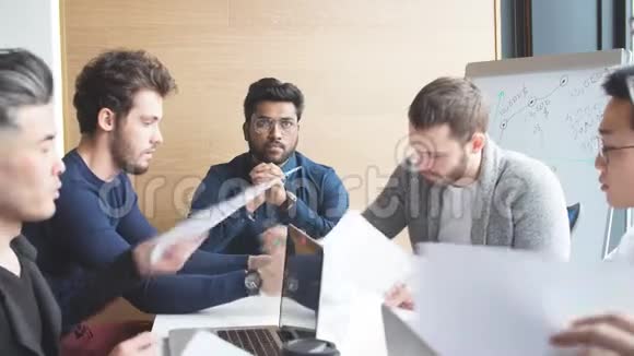 聪明的印度男人在工作地点与笔记本电脑正在向他的同事报告新的项目视频的预览图