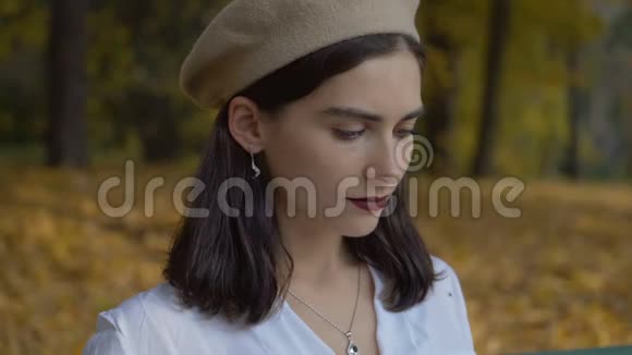 女性肖像特写秋天公园背景下的一个贝雷帽里的黑发女人女孩在看书4k视频的预览图