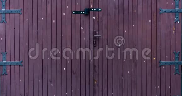在一个旧的带有大金属铰链的木制车库门前冬天大雪花飘落的延时视频4k视频的预览图