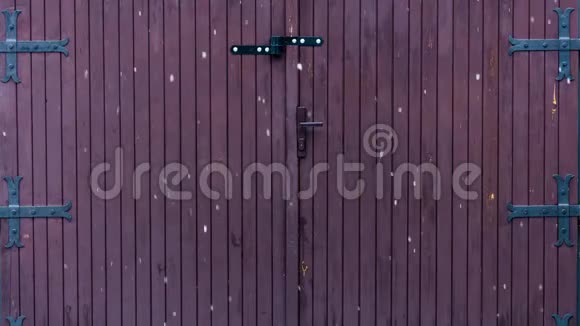 在一个旧的带有大金属铰链的木制车库门前冬天大雪花飘落的延时视频4k视频的预览图