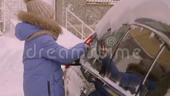交通冬天天气人和车辆的概念年轻女孩用刷子擦车上的雪视频的预览图