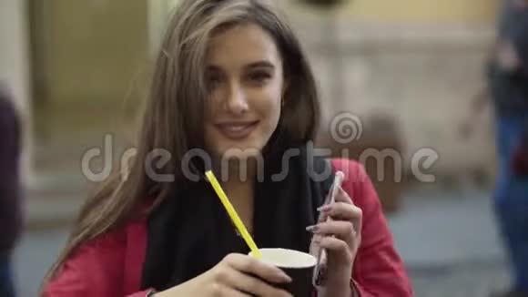 在街边的咖啡馆里坐着一个漂亮的女人喝着酒对着镜头微笑视频的预览图