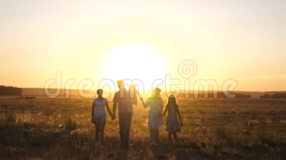 幸福的家庭在夕阳下漫步在田野里爸爸妈妈和女儿在阳光下在公园里散步儿童和视频的预览图