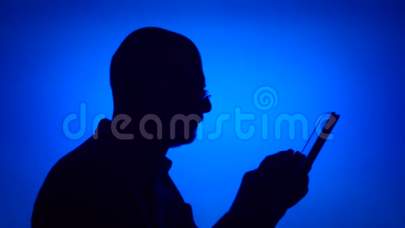 高级男士剪影在蓝色背景上使用平板电脑男性在网上浏览个人资料视频的预览图