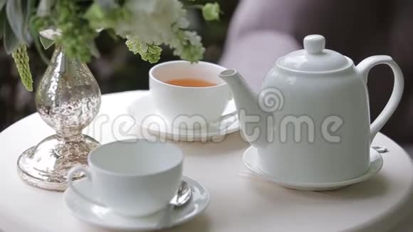 热茶放在白色的桌子上上面装饰着一束鲜花聚焦全景视频的预览图