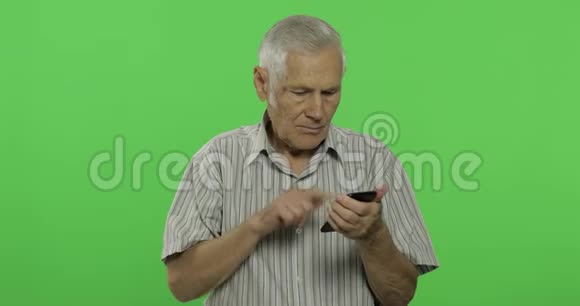 老人在智能手机上工作性感钥匙背景上英俊的老人视频的预览图
