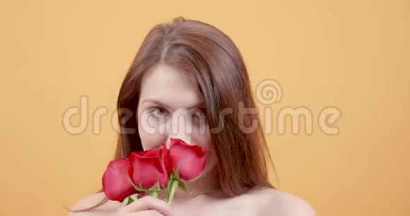年轻漂亮的女孩闻着一束玫瑰视频的预览图