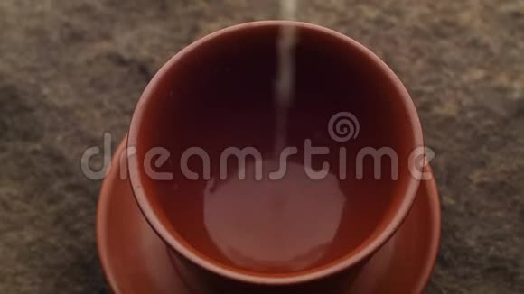 一股新鲜的热的绿茶在粗糙的天然石头上流入陶瓷碗里视频的预览图