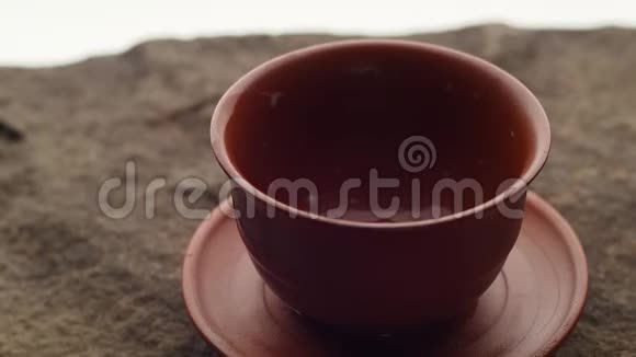 一股新鲜的热的绿茶在粗糙的天然石头上流入陶瓷碗里视频的预览图