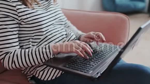 年轻女孩坐在沙发上里面有笔记本电脑自由职业者在家工作检查岗位写评论视频的预览图