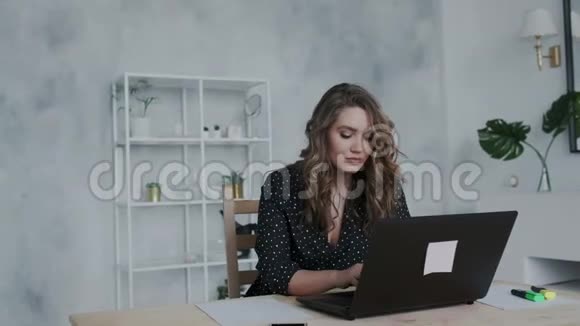 年轻的自然卷曲自信的黑发女孩穿着黑色连衣裙在家工作使用笔记本电脑远程同事工作视频的预览图