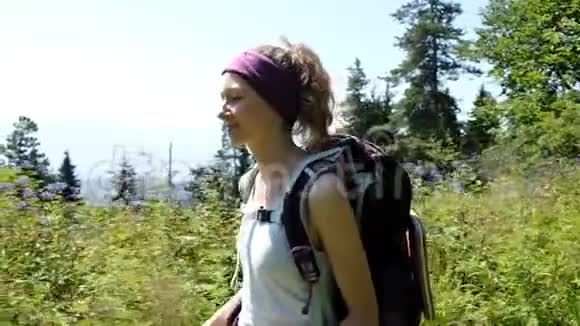 徒步旅行中的快乐女游客带着背包和微笑慢动作镜头移动视频的预览图