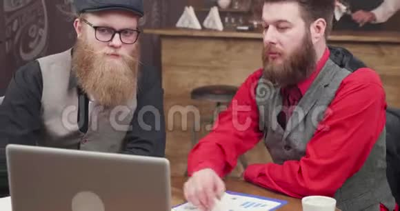 两个穿着老式咖啡屋的男人在网上视频电话中问候他们的同事视频的预览图