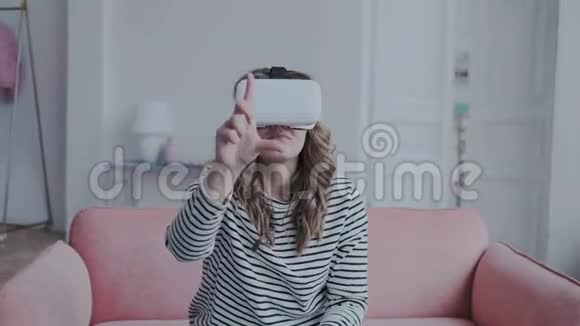 很有趣的女孩在室内探索虚拟现实眼镜她在与人交往的时候动了手指视频的预览图