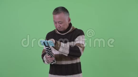 快乐成熟的日本男子vlog和显示电话视频的预览图
