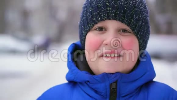 穿着蓝色羽绒服的少年笑冬天下着雪视频的预览图