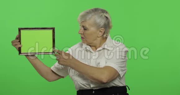 一位年长的妇女拿着一个带有绿色图像的框架老奶奶铬键视频的预览图