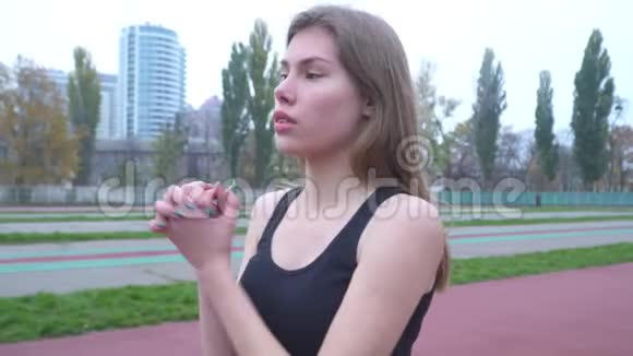 一个穿着紧身运动衫的年轻女孩在户外做热身运动视频的预览图