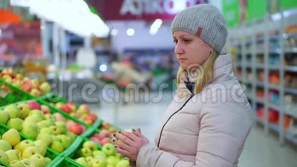 穿冬天衣服的女人在超市摘水果她看起来像苹果视频的预览图