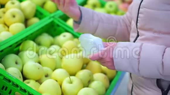 一个穿着冬衣的女人把青苹果放进包裹里的手她选择了最美味的视频的预览图