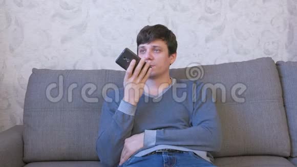 男人在坐在沙发上的手机上记录一条语音信息视频的预览图