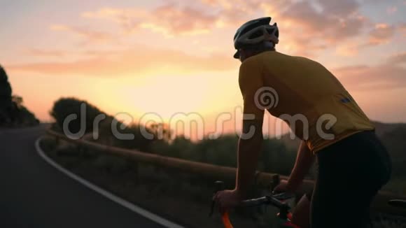 一个年轻的运动男子骑着自行车骑在山蛇形上戴着黄色的t恤头盔和运动设备后视视频的预览图