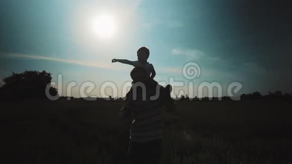 父亲把儿子扛在肩上日落时在麦田散步父亲节家庭观念视频的预览图