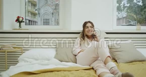 穿睡衣的女人在舒适的床上放松打电话心情愉快视频的预览图
