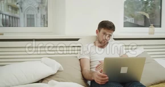非常集中的人在一个现代化的卧室里工作躺在床上视频的预览图