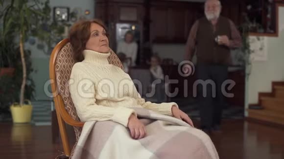 成熟的女人坐在摇椅上她的老丈夫给她端来一杯咖啡轻轻地按着他的手视频的预览图