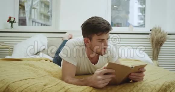 有魅力的年轻人在他舒适的卧室里看书放松视频的预览图