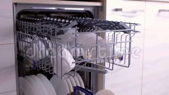 男人手推着篮子用肮脏的白色盘子关上洗碗机视频的预览图