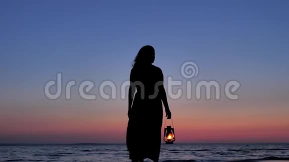 在日落的天空背景下穿着礼服的女性手中握着煤油灯视频的预览图