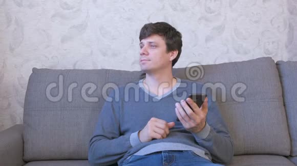 男人博主正坐在家里的沙发上在社交媒体上打字视频的预览图