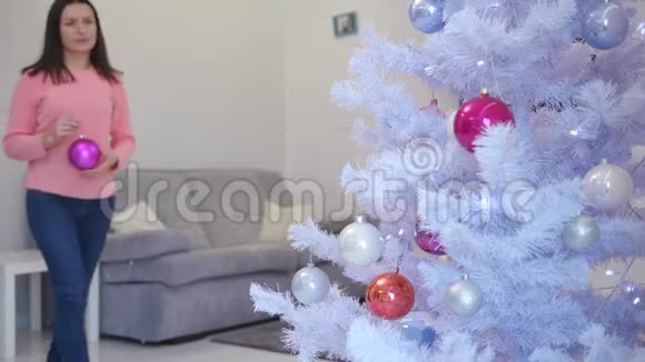 漂亮的年轻女人很高兴装饰圣诞树享受节日的精神视频的预览图