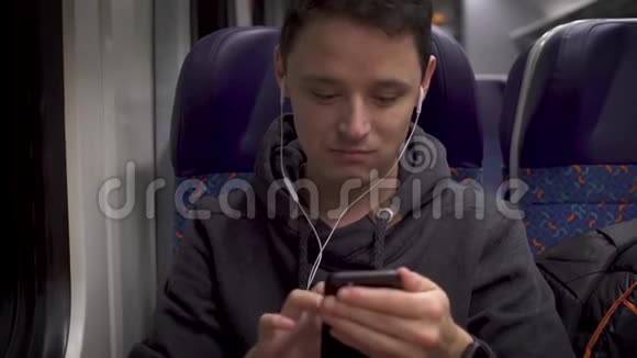 年轻人在火车上工作玩智能手机和音乐视频的预览图