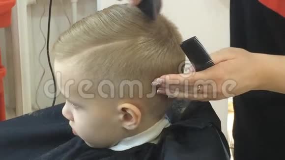 特写小男孩发型孩子的发型在儿童美发沙龙烘干头发定型吹风机儿童理发视频的预览图