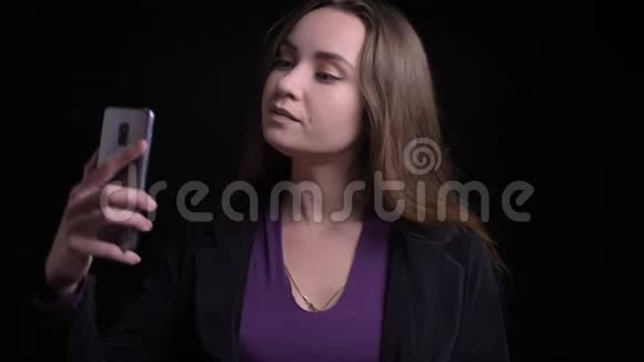 年轻迷人的白种人长发女性在手机上自拍的特写镜头背景与外界隔绝视频的预览图