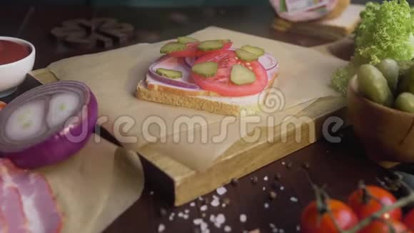 厨师的手在三明治里加入了切片培根和西红柿和泡菜在家做三明治做三明治视频的预览图