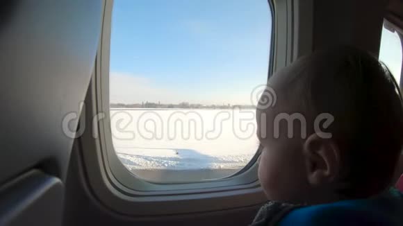 神奇的金发小男孩坐在飞机窗口附近看视频的预览图