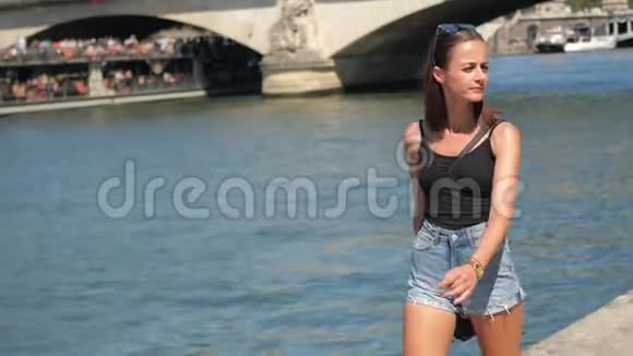 阳光明媚的一天年轻的法国女人沿着塞纳河在巴黎散步视频的预览图