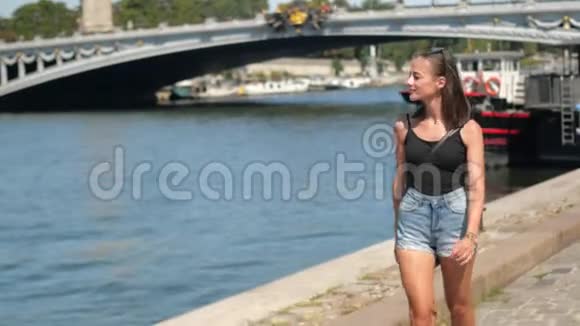 年轻的法国女人在阳光明媚的一天沿着塞纳河在巴黎散步视频的预览图