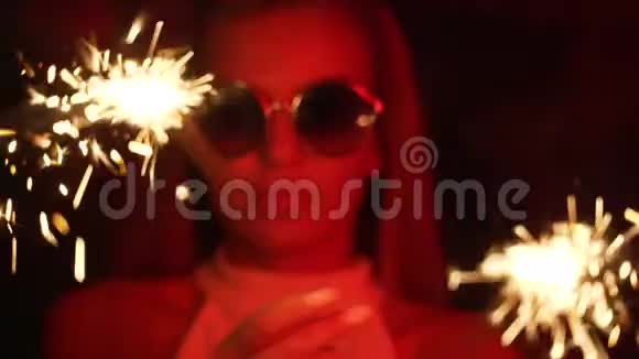女孩拿着闪闪发光的红色霓虹灯年轻漂亮的女人戴着眼镜手里拿着燃烧的孟加拉火视频的预览图