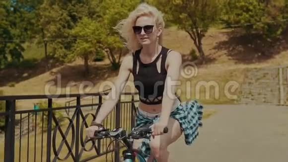 阳光明媚的夏日阳光明媚的阳光下美丽的年轻女子骑着自行车微笑视频的预览图