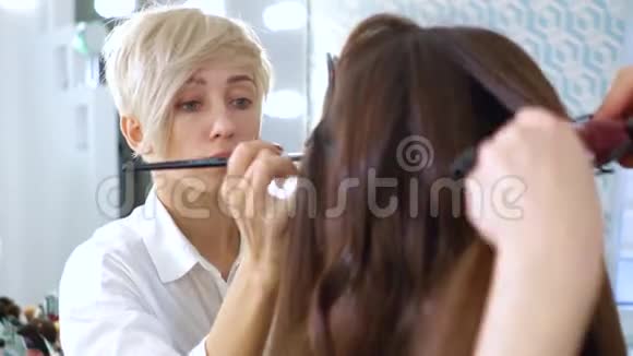 化妆师和理发师在展厅为年轻女性做专业造型视频的预览图