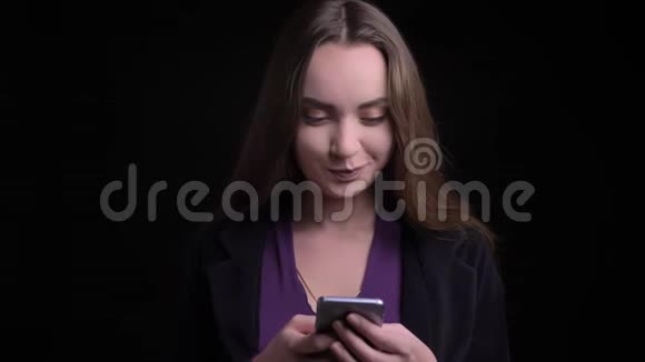 特写镜头年轻迷人的白种人女性在手机上发短信看着镜头笑着玩视频的预览图