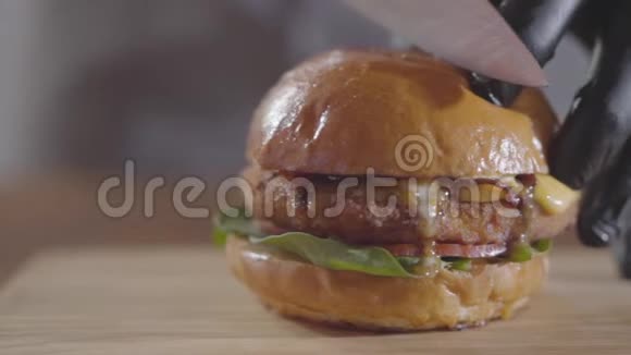厨师的手在黑色橡胶手套切割汉堡与大锋利的刀特写美味的食物准备果汁视频的预览图