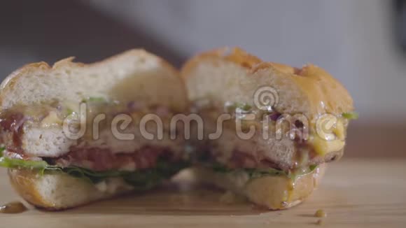 特写手中的汉堡和酱汁流出美味的食物美味可口的汉堡放在桌子上慢动作视频的预览图