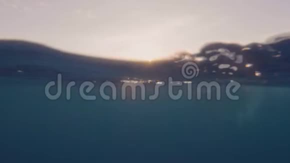 金色的阳光透过蓝色的海水和女人在水下游泳的女人右后方女子游泳视频的预览图